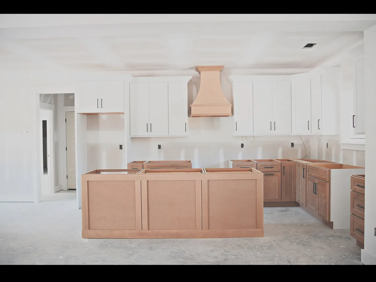 A Hucks Homes kitchen under construction, with a custom copper range hood over a large island